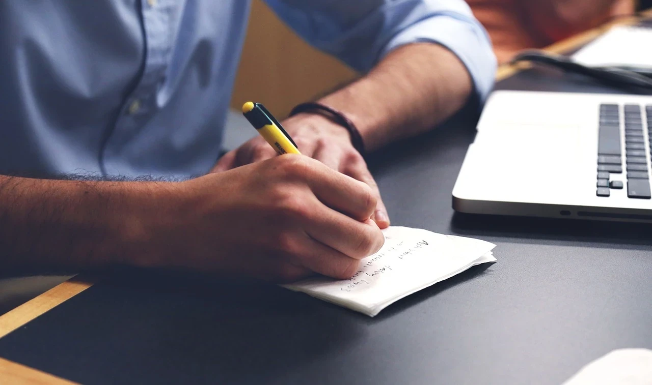 A person writing with a pen in a notebook